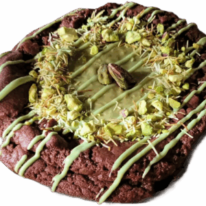 A decorated chocolate cookie with green drizzle and a nut on top.